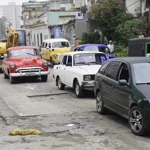Various vintage and modern cars are standing in line in the city