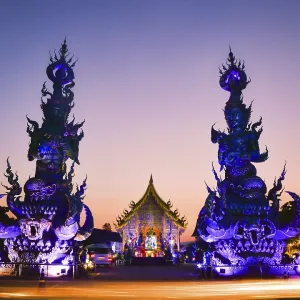 Vertical view vibrant Blue Temple Wat Rong Suea Ten in Chiang Rai Thailand at sunset with colorful glowing sculptures