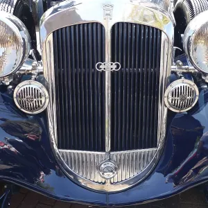 Front view of a classic car with double round headlights and shiny front grille
