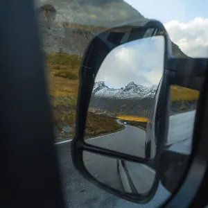 View of the fjord landscape through Campervan side mirror
