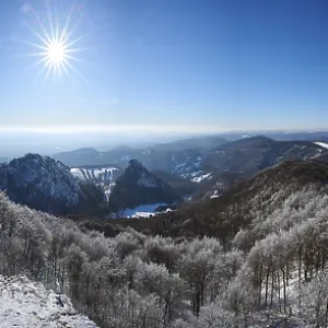 View over the hills and valleys from the mountain with hoarfrost on the branches in winter