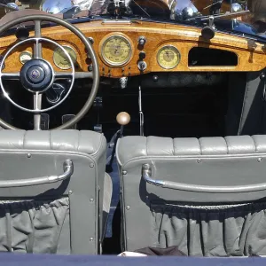 View of the interior of a vintage car with wooden elements and classic steering wheel