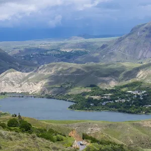 View of a lake nestled in mountainous landscape under cloudy sky