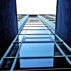 View looking up at a modern building with blue glass and strong vertical lines