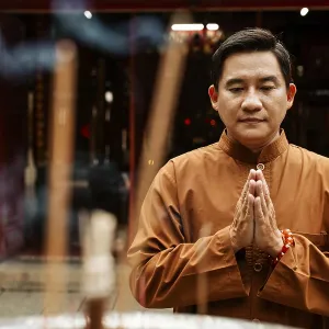 Front view man praying temple with incense Front view man praying temple with incense