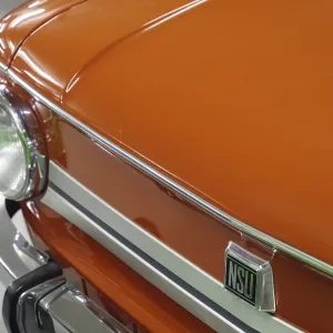 Front view of an orange-coloured NSU classic car with shiny details and headlights