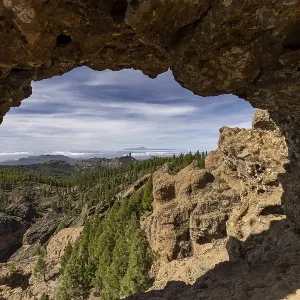 View through a rock arch to Roque Nublo and the Teide mountain peak on the neighbouring island of Tenerife View through a rock arch to Roque Nublo and the Teide mountain peak on the neighbouring island of Tenerife