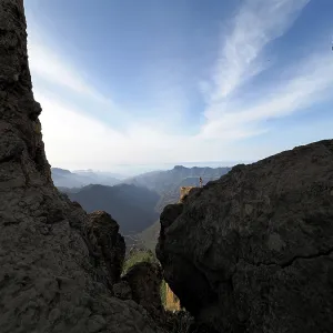 View through rocks of a vast mountain landscape under clear sky View through rocks of a vast mountain landscape under clear sky