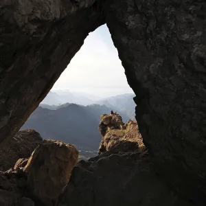 View through a rocky frame of a distant mountain landscape View through a rocky frame of a distant mountain landscape