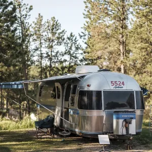 Front view of a silver Airstream camper in a forested area