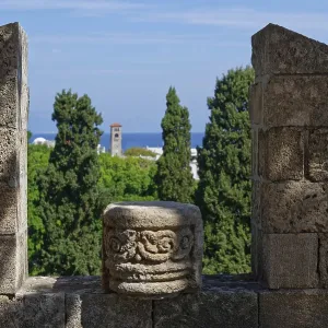 View from a stone wall with battlements of green trees and the distant sea under a blue sky