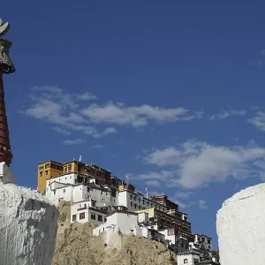 View through two stupas towards Thiksey monastery on a hill under blue sky View through two stupas towards Thiksey monastery on a hill under blue sky