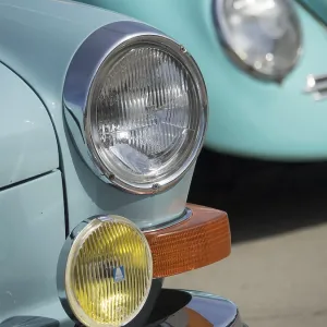 Front view of two turquoise and blue colored vintage cars with chrome headlights Front view of two turquoise and blue colored vintage cars with chrome headlights