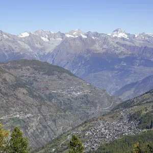 View of a valley with settlements surrounded by majestic mountains