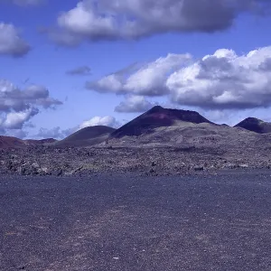 View of a vast volcanic landscape with colorful mountains under a cloudy sky