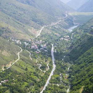 View of a village in the valley surrounded by green hills and a river