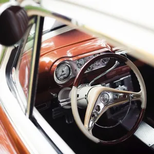 View of a vintage car interior showing the steering wheel and dashboard in St