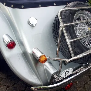 Back view of a vintage car with spare tires and chromed elements on cobblestones