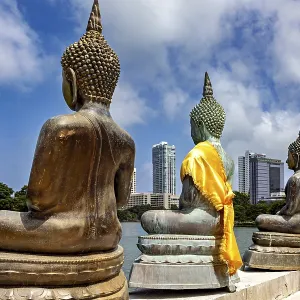 Back views of Buddha statues with yellow fabrics in front of a modern city Back views of Buddha statues with yellow fabrics in front of a modern city