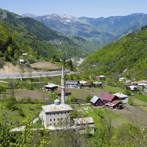Village with a mosque in a green valley surrounded by mountains