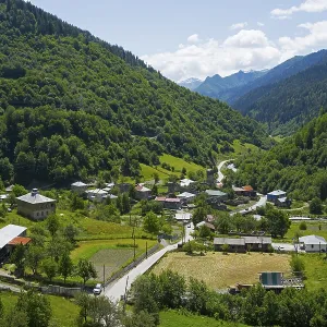 Village nestled in a green valley with mountains in the background