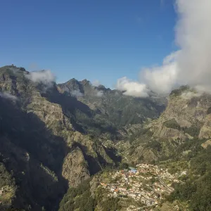 Village nestled in a valley surrounded by high mountains and clouds