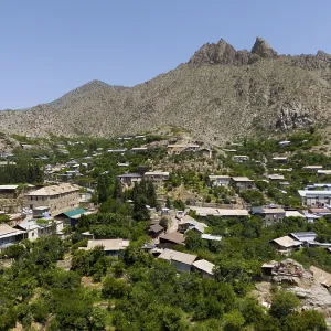 Village surrounded by lush vegetation and high mountains in a sunny landscape