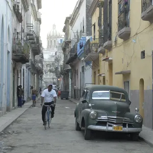 Vintage car and cyclist in an alley in the old part of Havana Vintage car and cyclist in an alley in the old part of Havana