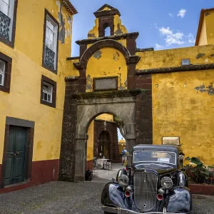 Vintage car parked in front of yellow gate and wall Vintage car parked in front of yellow gate and wall
