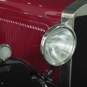 Vintage car in red with chrome headlights and radiator grille full of character
