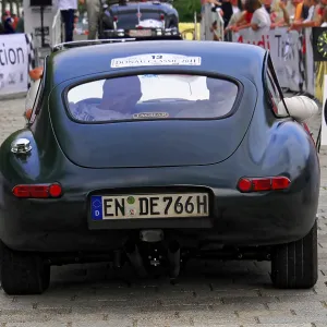 Vintage green jaguar car seen from behind with spectators at an event