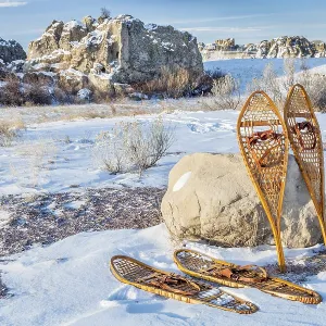 Vintage Huron and Bear Paw snowshoes in winter scenery on a parking lot or trailhead