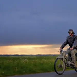 Vintage motorcyclist in front of a dramatic cloudy sky