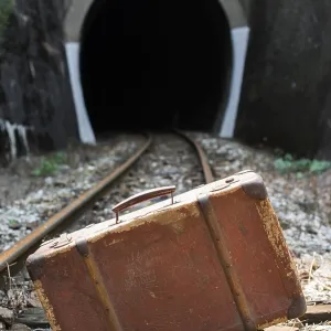 Vintage suitcase on railway road and tunnel