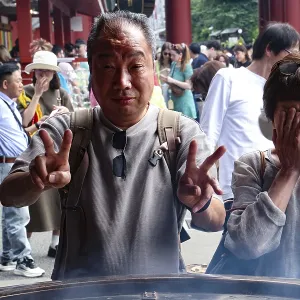 Visitors to Senso-ji Temple pose in front of a large fire bowl Visitors to Senso-ji Temple pose in front of a large fire bowl