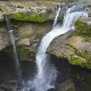 Water falling into a river over moss-covered rocks Water falling into a river over moss-covered rocks