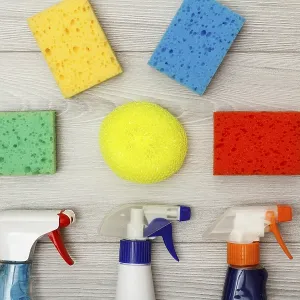 Water sprayers and color synthetic sponges for cleaning on gray wooden background Water sprayers and color synthetic sponges for cleaning on gray wooden background