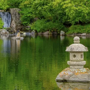A waterfall and a stone lantern next to a tranquil pond in the Nikka Yuko Japanese Garden in Lethbridge A waterfall and a stone lantern next to a tranquil pond in the Nikka Yuko Japanese Garden in Lethbridge