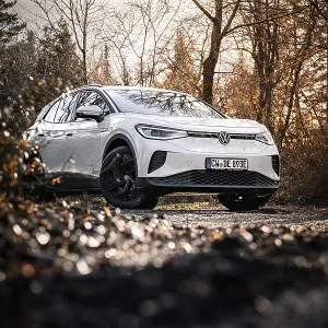 White car in autumn forest with warm light and bare trees