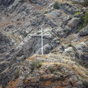 White commemorative cross on the top of the hill against the background of the mountain landscape