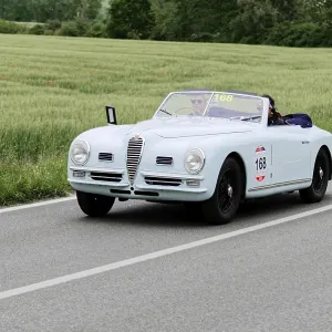 A white convertible classic car drives on a country road A white convertible classic car drives on a country road