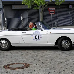 White convertible with an elderly man driving at a classic car event