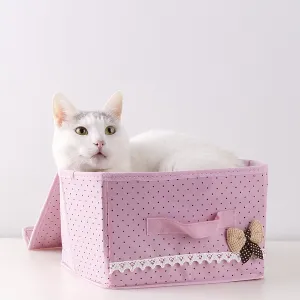 White domestic big cat seating inside the small pink starage box against the wall