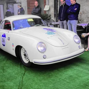 White Porsche Coupe at a classic car rally on green carpet White Porsche Coupe at a classic car rally on green carpet