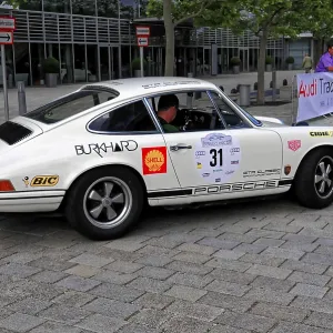 White Porsche with rally stickers from the side at a classic car event