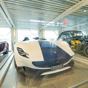 White sports car and classic car in a brightly lit exhibition hall
