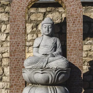White stone statue of a Buddha on masonry background White stone statue of a Buddha on masonry background