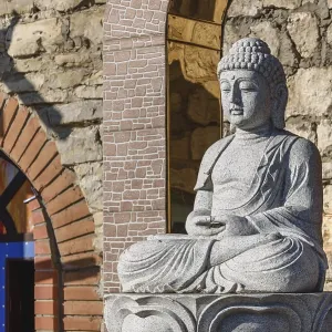 White stone statue of a Buddha on masonry background White stone statue of a Buddha on masonry background