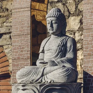 White stone statue of a Buddha on masonry background White stone statue of a Buddha on masonry background