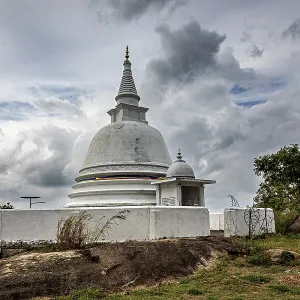 White stupa against dramatic sky surrounded by natural terrain White stupa against dramatic sky surrounded by natural terrain
